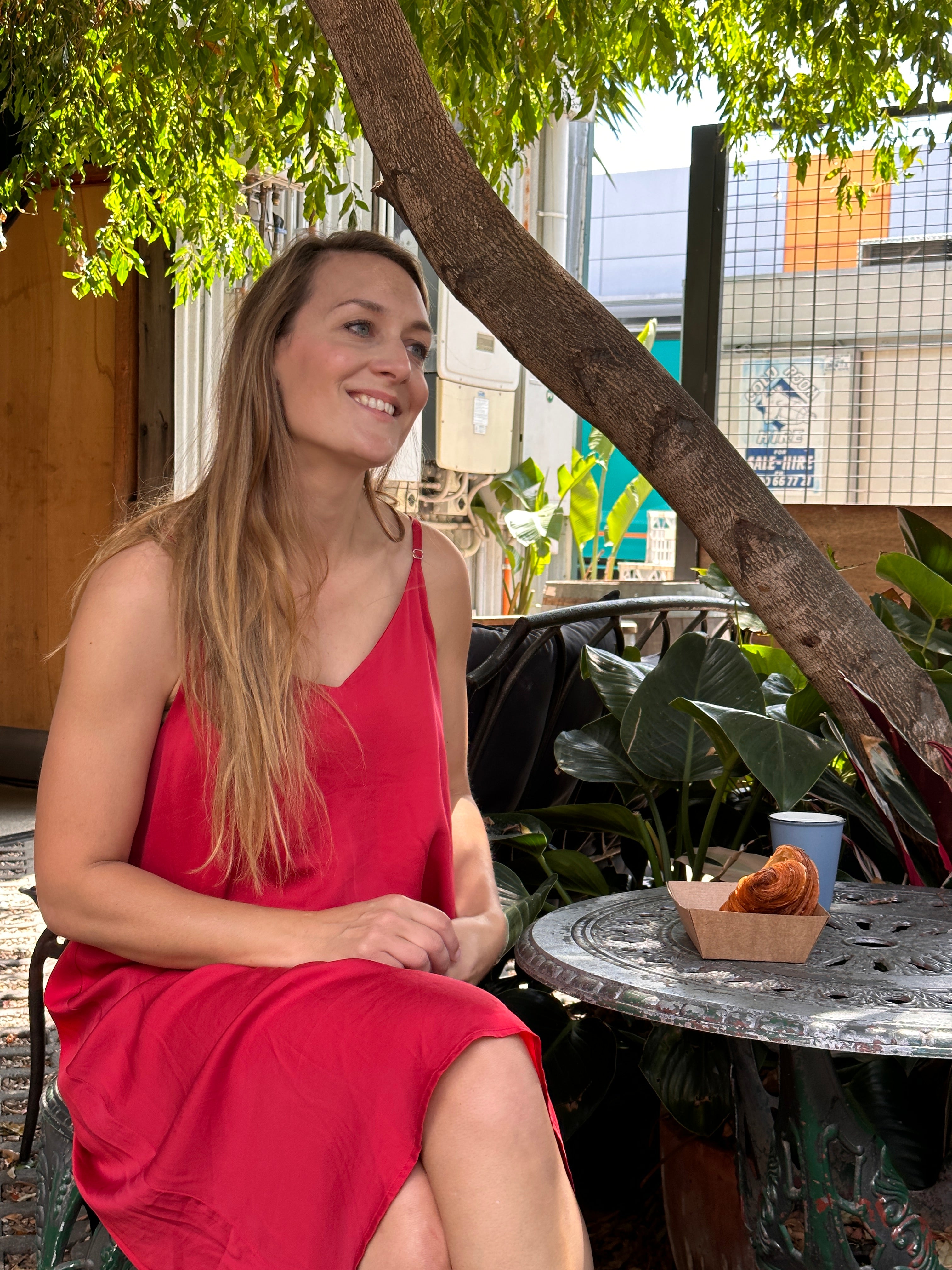 Beautiful girl wearing a red nightie eating a croissant near a French table