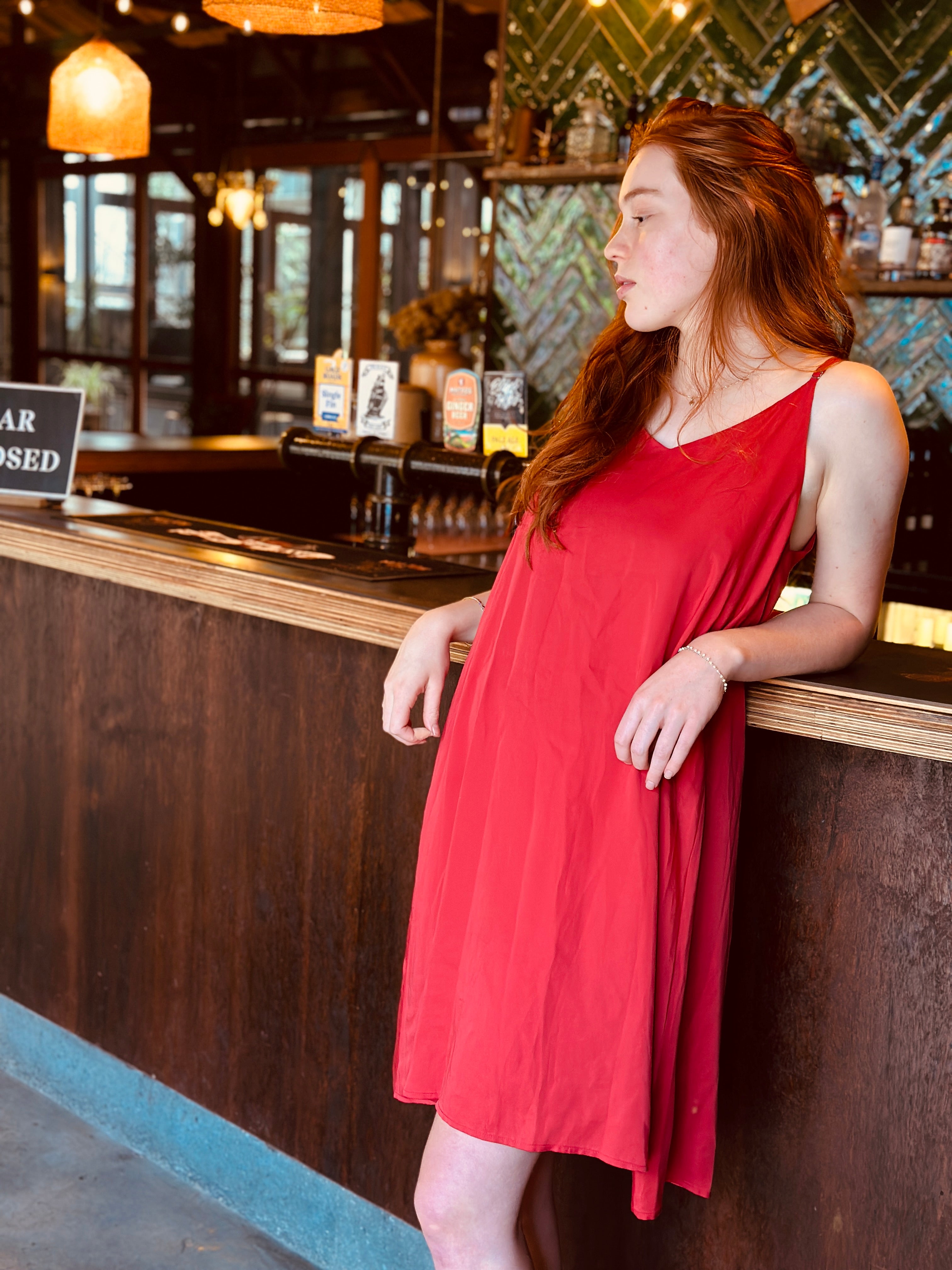 Beautiful girl wearing a red nightie leaning again a bar